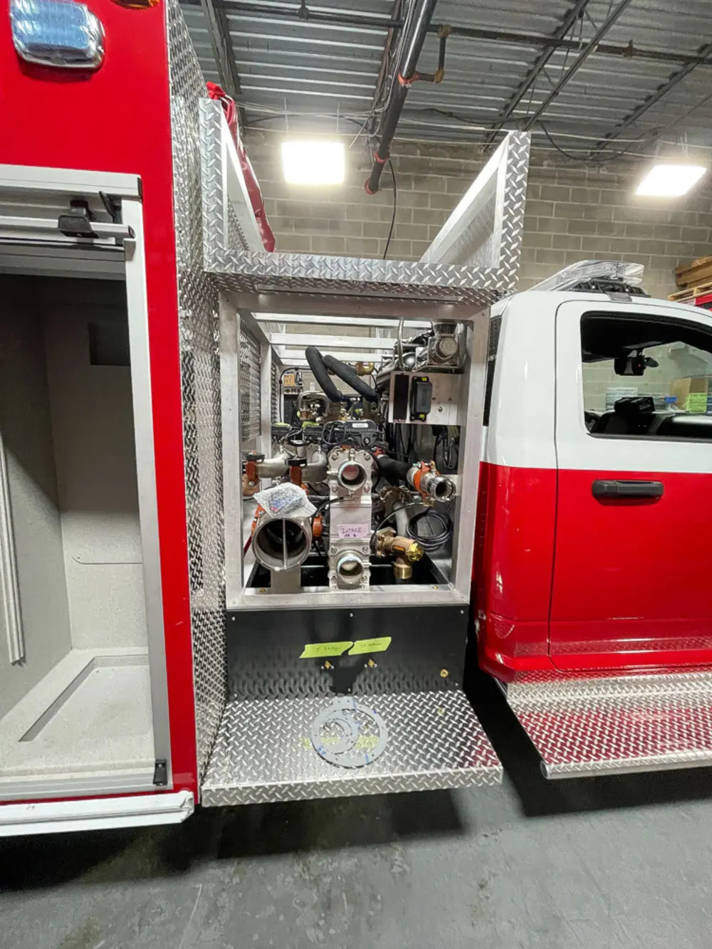 Exterior view of small fire truck showing cab, body compartments, and wheel/tire area.